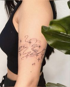 a woman with a tattoo on her arm is looking at the camera and holding a plant