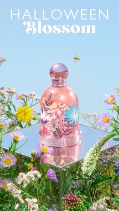 a pink bottle sitting on top of a lush green field filled with wildflowers