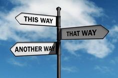 three street signs pointing in opposite directions against a blue sky with clouds