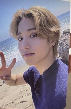 a young man making the peace sign with his hand on top of him at the beach