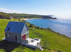 an aerial view of a house on the coast with water in the background and green grass to the foreground