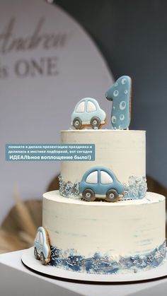 a three tiered cake with cars on top and the number one frosted in blue