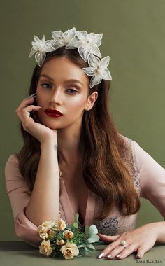 a woman sitting at a table with flowers in her hair and wearing a flower crown