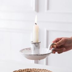 a person holding a candle in a silver bowl