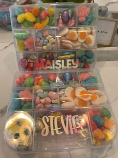 plastic containers filled with candy and candies on top of a white counter next to a potted plant