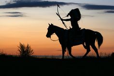 the silhouette of a person on a horse with an arrow in his hand and holding a bow