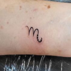 a small tattoo on the arm of a woman's left arm, which has an m in it