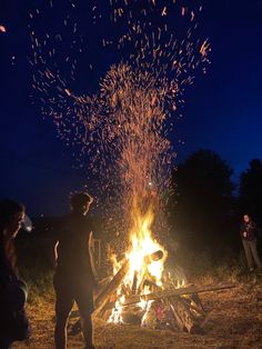 people standing around a campfire with lots of sparklers in the sky above them