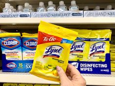 a hand is holding two packets of glycolt detergent wipes on a shelf