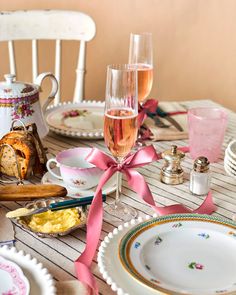 the table is set with dishes, cups, and wine glasses for an afternoon tea party