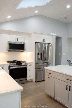 a kitchen with white cabinets and stainless steel appliances in the center, along with a skylight