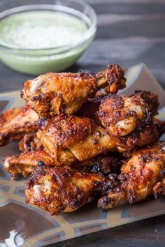 some chicken wings are on a plate with dipping sauce