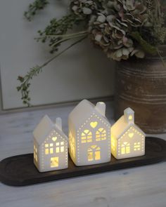 three lit houses on a tray with flowers in the background