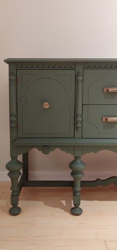 a green dresser sitting on top of a hard wood floor next to a white wall