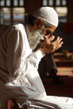 an old man sitting on the ground praying