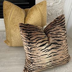 two zebra print pillows sitting next to each other on the floor in front of a fireplace