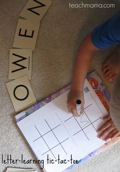 a young child is doing crossword puzzles on the floor with letters and numbers in front of them