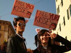 two people holding up signs in front of a building that says free your kissers