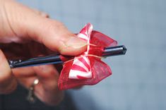 a person holding a cell phone with a candy cane on it's bowtie