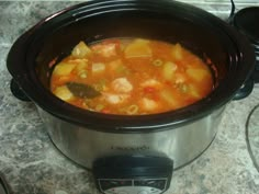 a crock pot filled with soup sitting on top of a counter next to an electric pressure cooker