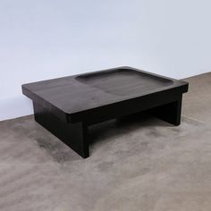 a black coffee table sitting on top of a cement floor