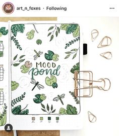 an open notebook with the words mood bound written in green leaves and dragonflies on it