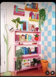 a pink shelf with books and plants on it