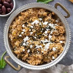 a bowl filled with rice and vegetables next to olives