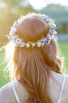 a woman with long red hair wearing a flower crown on her head and back to the camera