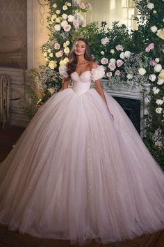 a woman in a wedding dress standing next to a flower covered wall with flowers on it