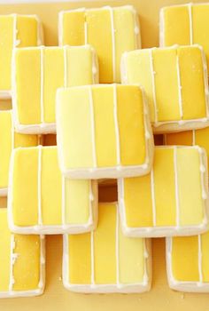 there are many yellow and white cookies on the table together with icing to make them look like they have been cut into squares