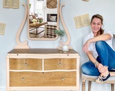 a woman sitting on a chair in front of a dresser with books flying around her