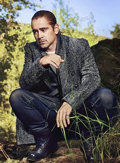 a man sitting on top of a rock next to tall grass