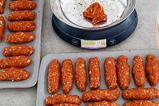 several trays filled with hot dogs next to an air fryer and other food items