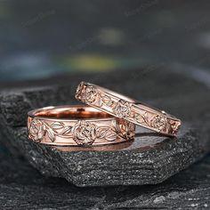 two rose gold wedding bands on top of a rock with the words love written in it