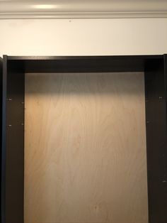 an empty shelf with some wood on it in a room that has white walls and black trim around the edges