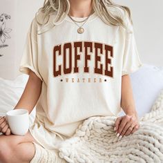 Comfort Colors® Coffee Weather T-Shirt, Coffee Lover Shirt, Coffee Addict Shirt, Coffee Colic Shirt, Cute Fall Shirt, Retro Fall Shirt A Comfort Colors shirt is a type of casual t-shirt that is known for its softness, relaxed fit, and muted color palette. Typically made from 100% cotton, these shirts have a vintage feel and are often favored for their comfortable, worn-in look. This classic unisex jersey short sleeve and long sleeve tees fits like a well-loved favorite. Soft cotton and quality p Coffee Short Sleeve Shirt With Letter Print, Coffee Colored Short Sleeve Shirt With Letter Print, Coffee Colored Cotton Slogan Top, Casual Coffee Tops With Letter Print, Casual Coffee Colored Top With Letter Print, Casual Coffee-colored Tops With Letter Print, Casual Coffee-colored Letter Print Tops, Casual Coffee-colored Top With Letter Print, Coffee-colored Cotton Tops With Slogan