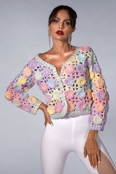 a woman in white pants and a colorful crochet sweater is posing for the camera