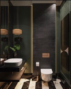 a modern bathroom with black walls and marble flooring, two sinks and a toilet