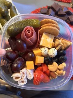 a plastic container filled with lots of different types of snacks and fruit on top of each other