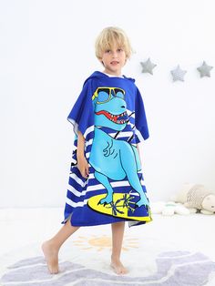 a little boy in a blue dinosaur dress is standing on the floor with his feet up