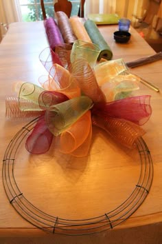 a table topped with lots of different colored ribbons on top of a wooden table next to a window