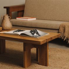 a wooden table sitting on top of a carpeted floor next to a brown couch