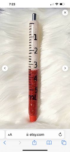 a tube of lipstick sitting on top of a white fur covered floor next to a ruler