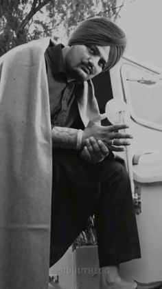 a black and white photo of a man sitting on a toilet with his hand in his mouth