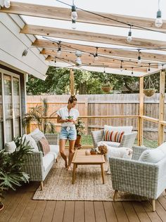 a woman is standing on the porch in her backyard