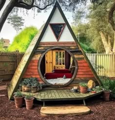 a small wooden cabin with a red couch in the center and potted plants around it