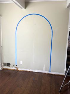 an empty room with a blue arch painted on the wall and hard wood flooring