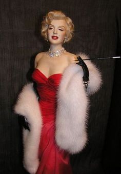 a woman in a red dress and white fur stoler holding a black stick with her right hand