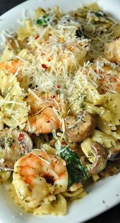 pasta with shrimp, mushrooms and parmesan cheese in a white bowl on a table